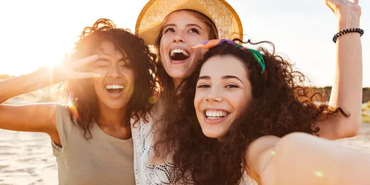 Две счастливые подруги смеются и поддерживают друг друга.